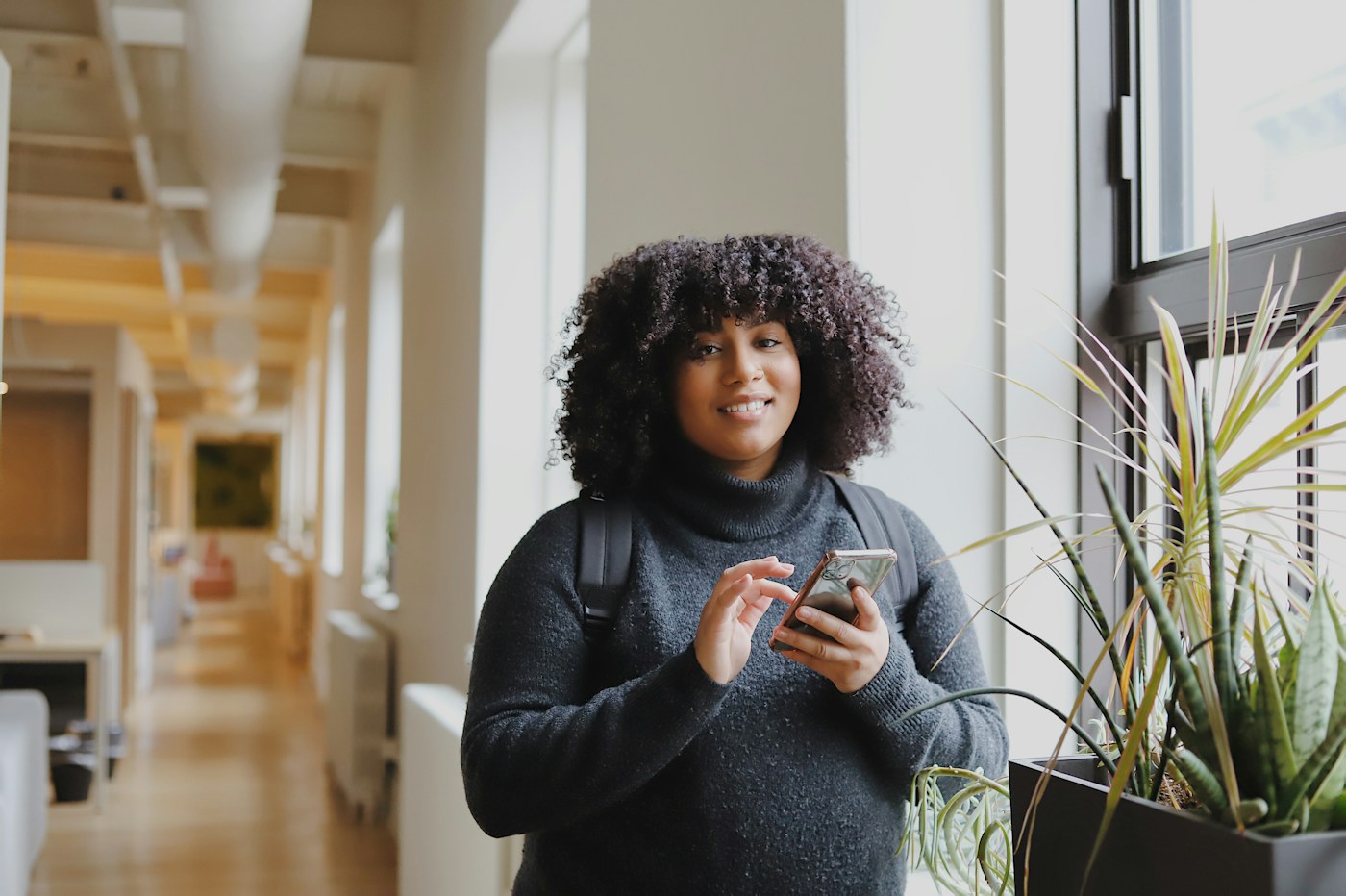 Une collaboratrice consulte son téléphone dans un couloir